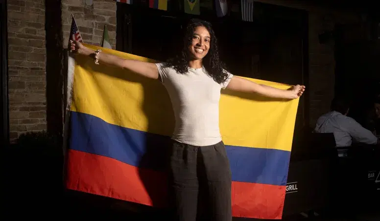 A portrait of a person while raising a Colombian flag at Bar 43 in Queens