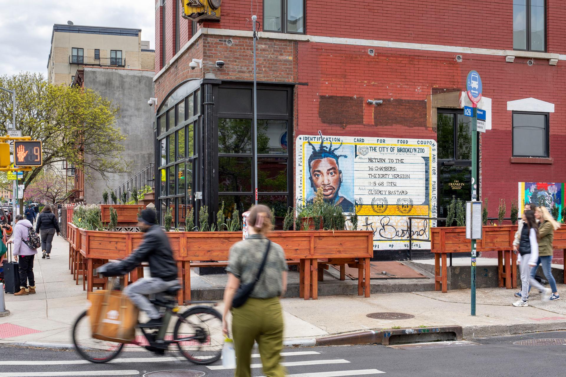 a group of people walking down a street next to a building with mural